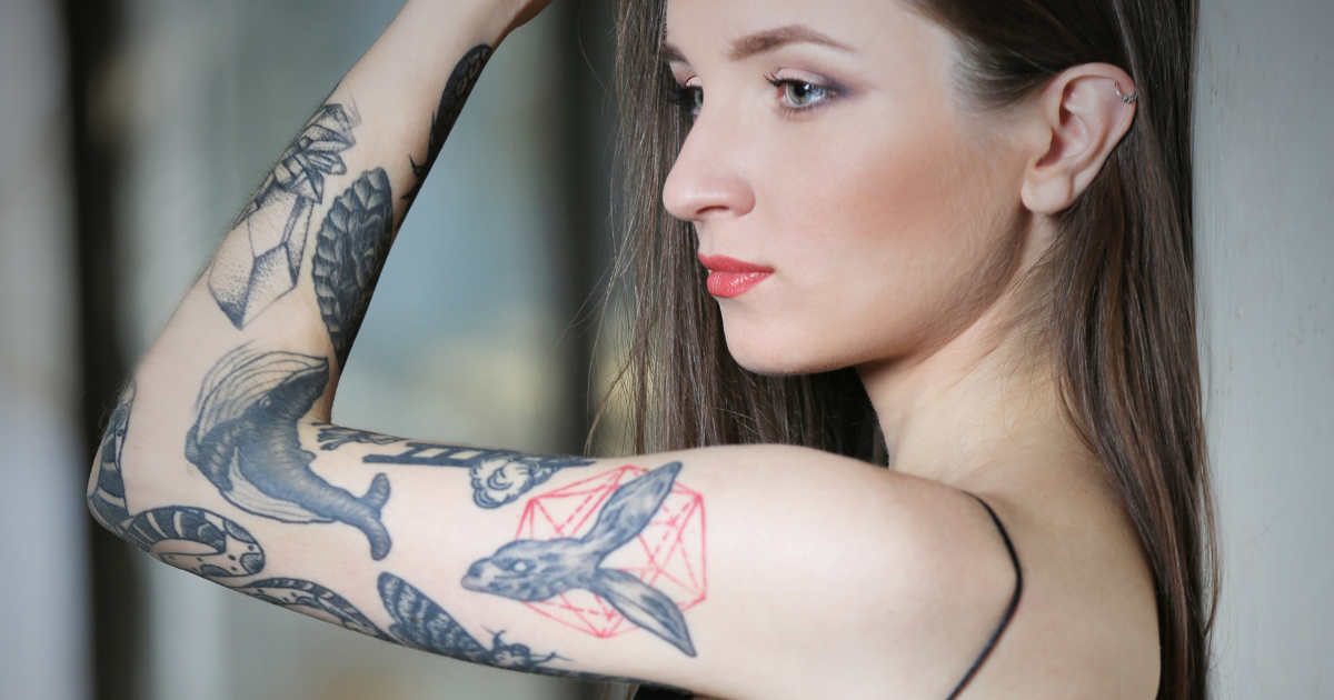 woman with tattoos thinking about laser hair removal.
